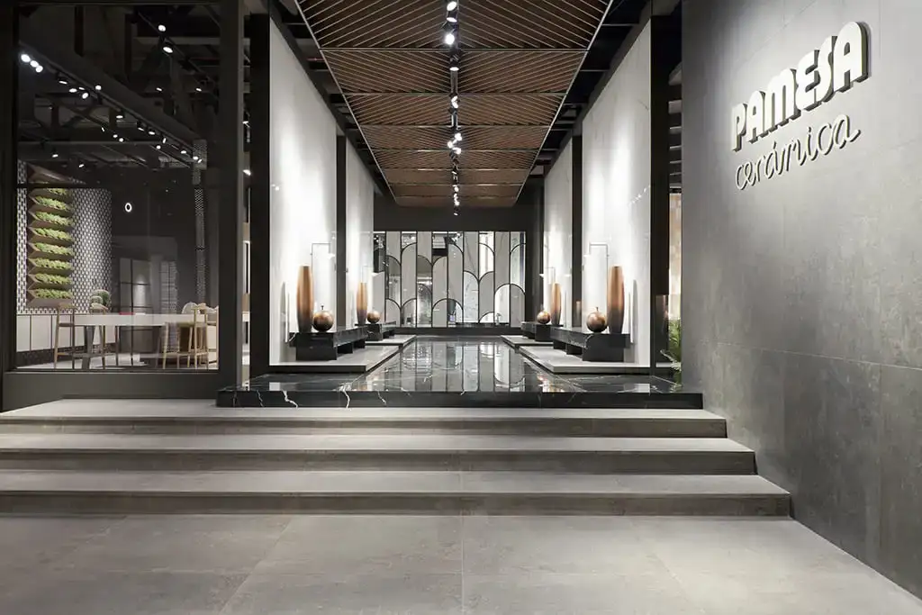 Exposición de Pamesa Cerámica, con su logotipo en la pared y pavimento porcelánico gris